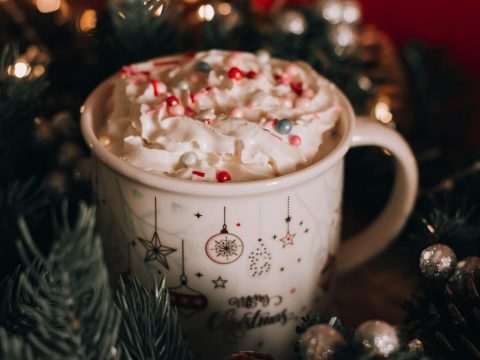 A Christmas cup full of hot chocolate surrounded by Christmas decorations
