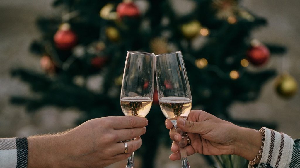 Two people holding champagne glasses with a Christmas tree in the background